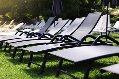 Photo of Many sunbeds on green grass outdoors, closeup