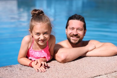 Photo of Happy father and his daughter resting in swimming pool outdoors. Family vacation