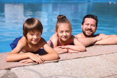 Photo of Happy father and his kids resting in swimming pool outdoors. Family vacation