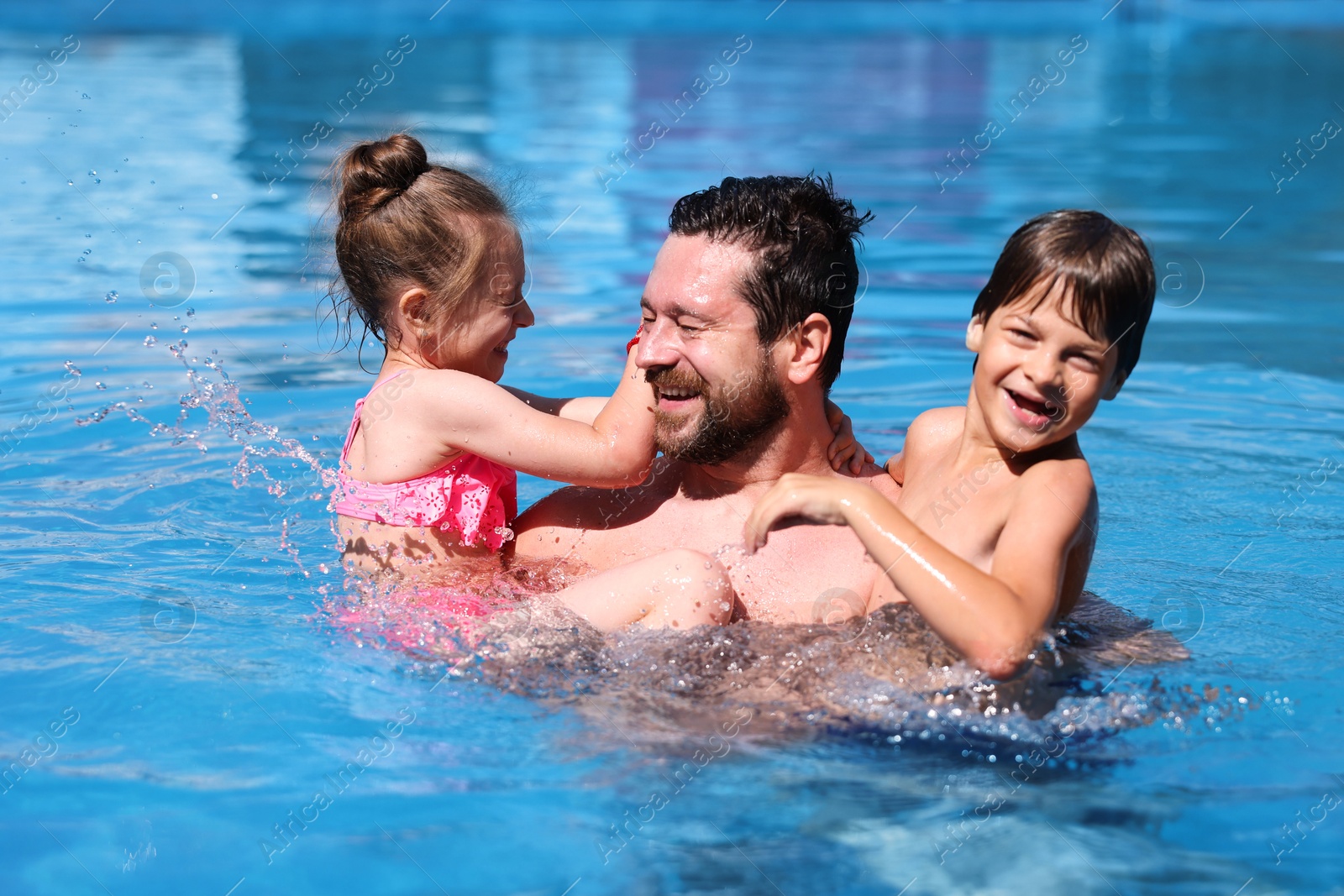 Photo of Happy father and his kids resting in swimming pool outdoors. Family vacation