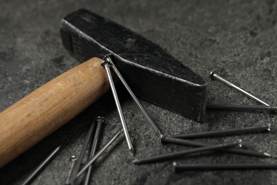 Photo of Hammer and metal nails on grey table, closeup