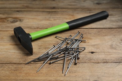Photo of Hammer and metal nails on wooden table, closeup