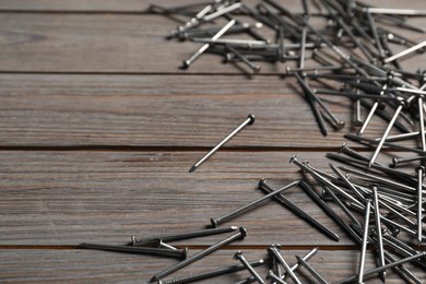 Photo of Many metal nails on wooden table, closeup. Space for text