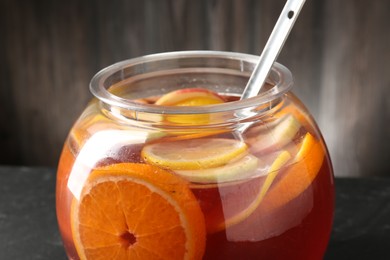 Photo of Fruity punch on black table, closeup. Refreshing drink