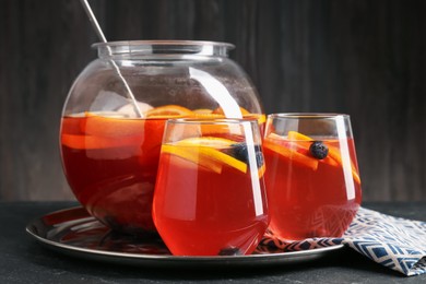 Photo of Fruity punch on black table, closeup. Refreshing drink