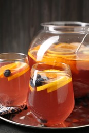 Photo of Fruity punch on black table, closeup. Refreshing drink