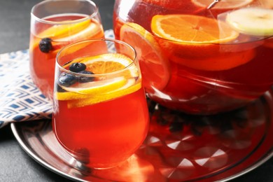Photo of Fruity punch on black table, closeup. Refreshing drink