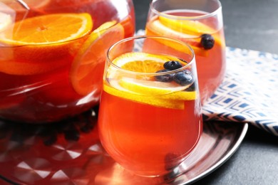 Photo of Fruity punch on black table, closeup. Refreshing drink