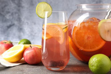 Photo of Punch and fresh fruits on grey table, closeup. Refreshing drink