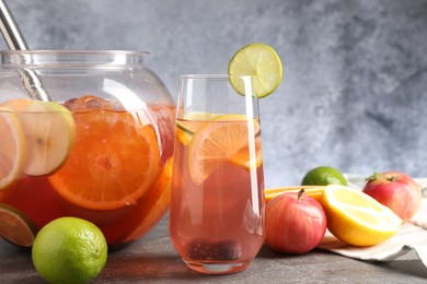 Photo of Punch and fresh fruits on grey table, closeup. Refreshing drink