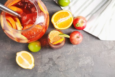 Photo of Punch and fresh fruits on grey table, flat lay with space for text. Refreshing drink