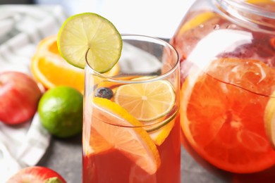 Photo of Punch and fresh fruits on grey table, closeup. Refreshing drink