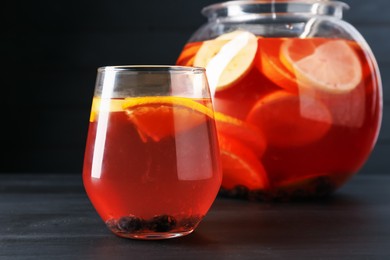 Photo of Fruity punch on black wooden table, closeup. Refreshing drink