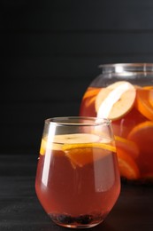 Photo of Fruity punch on black wooden table, closeup. Refreshing drink