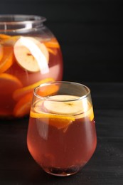 Photo of Fruity punch on black wooden table, closeup. Refreshing drink