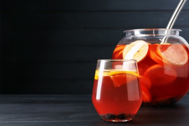 Photo of Fruity punch on black wooden table, space for text. Refreshing drink
