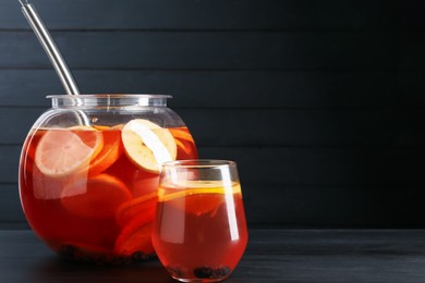 Photo of Fruity punch on black wooden table, space for text. Refreshing drink