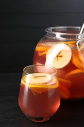 Photo of Fruity punch on black wooden table, closeup. Refreshing drink