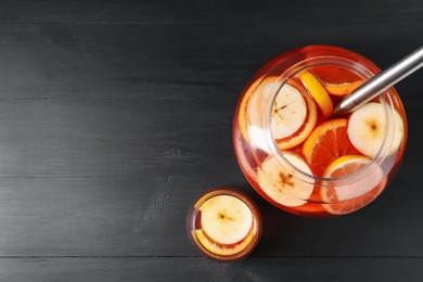 Photo of Fruity punch on black wooden table, flat lay with space for text. Refreshing drink