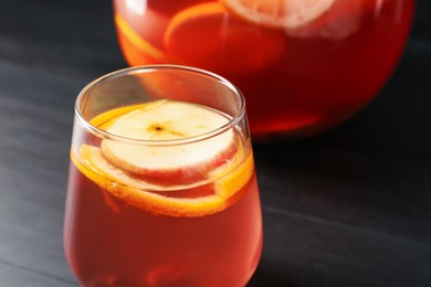 Photo of Fruity punch on black wooden table, closeup. Refreshing drink