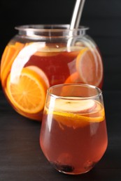Photo of Fruity punch on black wooden table, closeup. Refreshing drink
