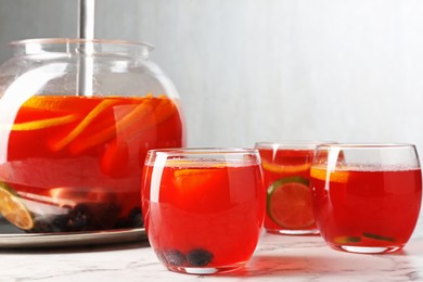Photo of Fruity punch on white marble table, closeup. Refreshing drink