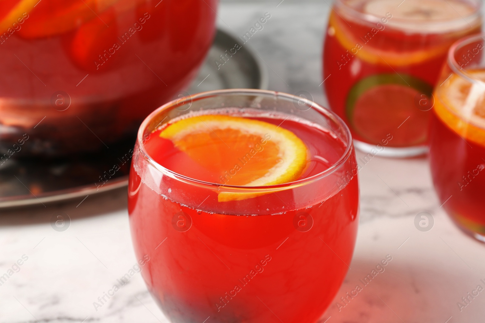 Photo of Fruity punch on white marble table, closeup. Refreshing drink
