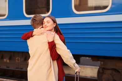 Photo of Goodbye. Lovely couple hugging on platform of railway station, space for text