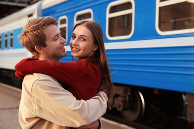 Photo of Goodbye. Lovely couple hugging near train outdoors, space for text