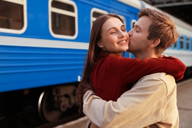 Photo of Goodbye. Lovely couple hugging near train outdoors, space for text
