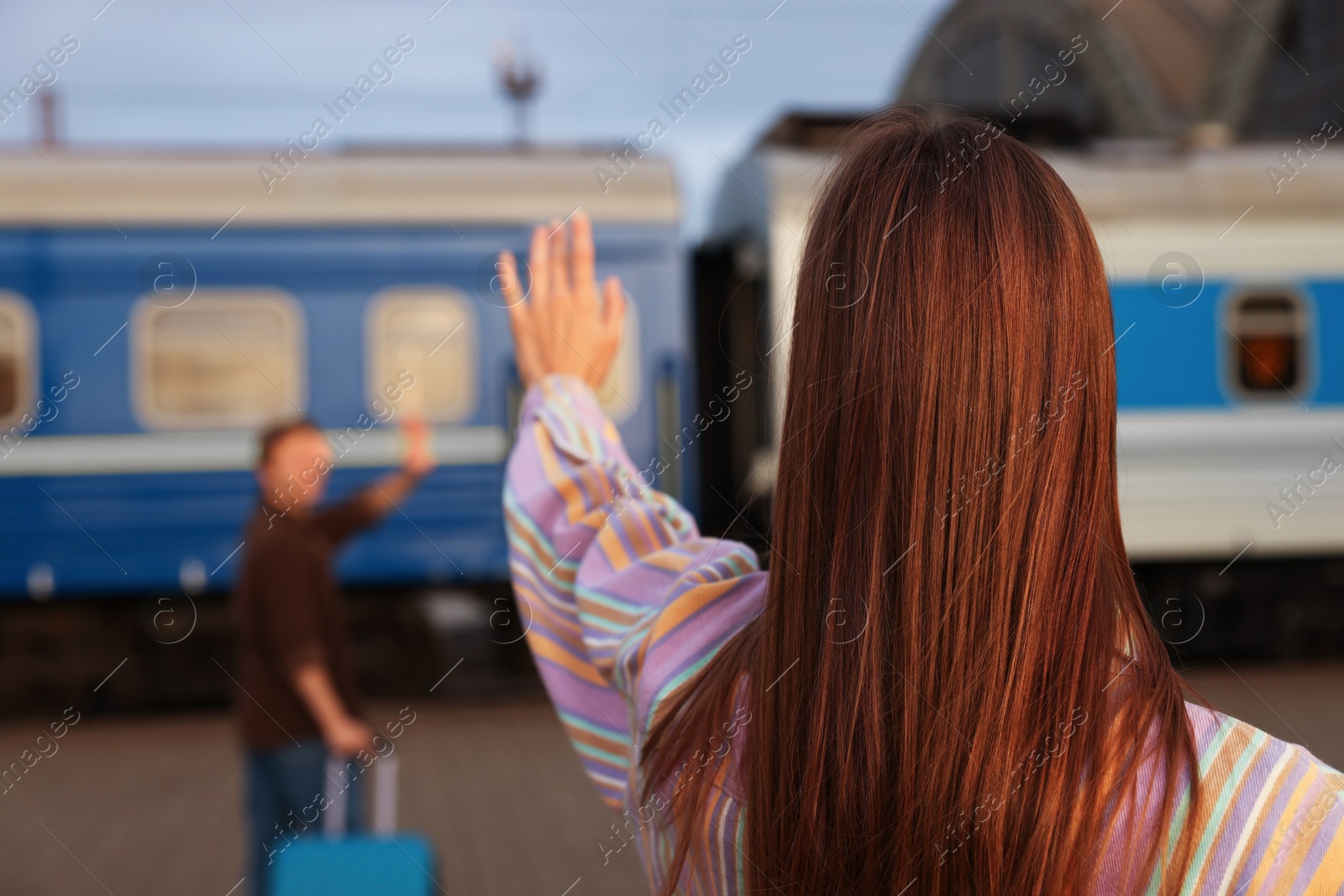 Photo of Goodbye. Woman waving to her boyfriend on platform of railway station, selective focus