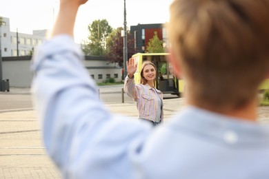 Photo of Goodbye. Woman waving to her boyfriend outdoors, selective focus