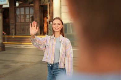 Photo of Goodbye. Woman waving to her boyfriend outdoors, selective focus