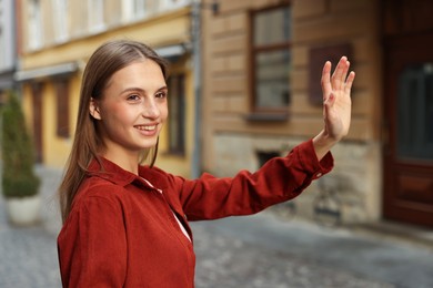 Photo of Goodbye. Happy woman waving on city street