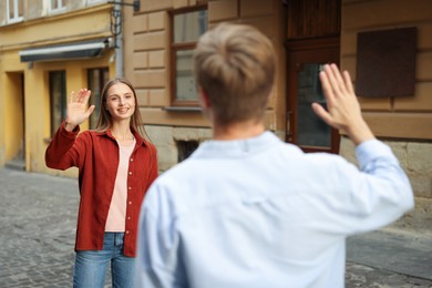 Photo of Goodbye. Man waving to his girlfriend on city street, selective focus