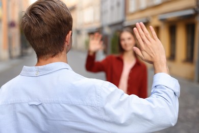 Photo of Goodbye. Man waving to his girlfriend on city street, selective focus