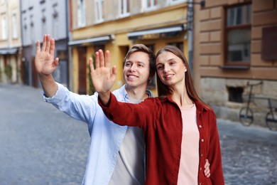 Photo of Goodbye. Lovely couple waving on city street