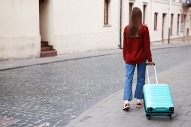 Photo of Goodbye. Woman with luggage walking outdoors, back view. Space for text