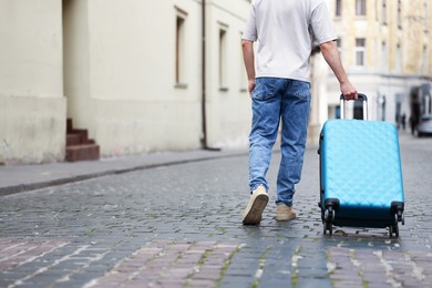 Photo of Goodbye. Man with luggage walking outdoors, closeup. Space for text