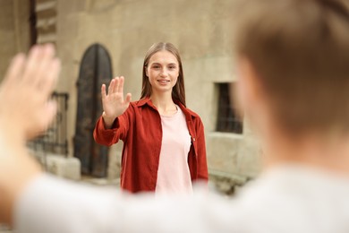 Photo of Goodbye. Man waving to his girlfriend outdoors, selective focus