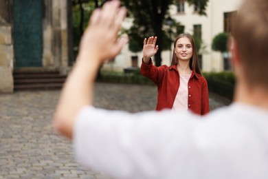 Photo of Goodbye. Man waving to his girlfriend outdoors, selective focus