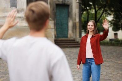 Photo of Goodbye. Man waving to his girlfriend outdoors, selective focus