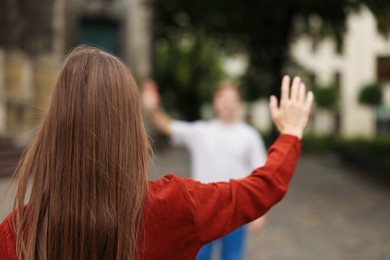 Photo of Goodbye. Woman waving to her boyfriend outdoors, selective focus