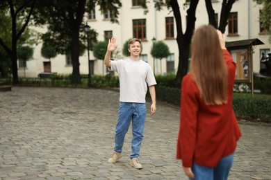 Photo of Goodbye. Woman waving to her boyfriend outdoors, selective focus. Space for text