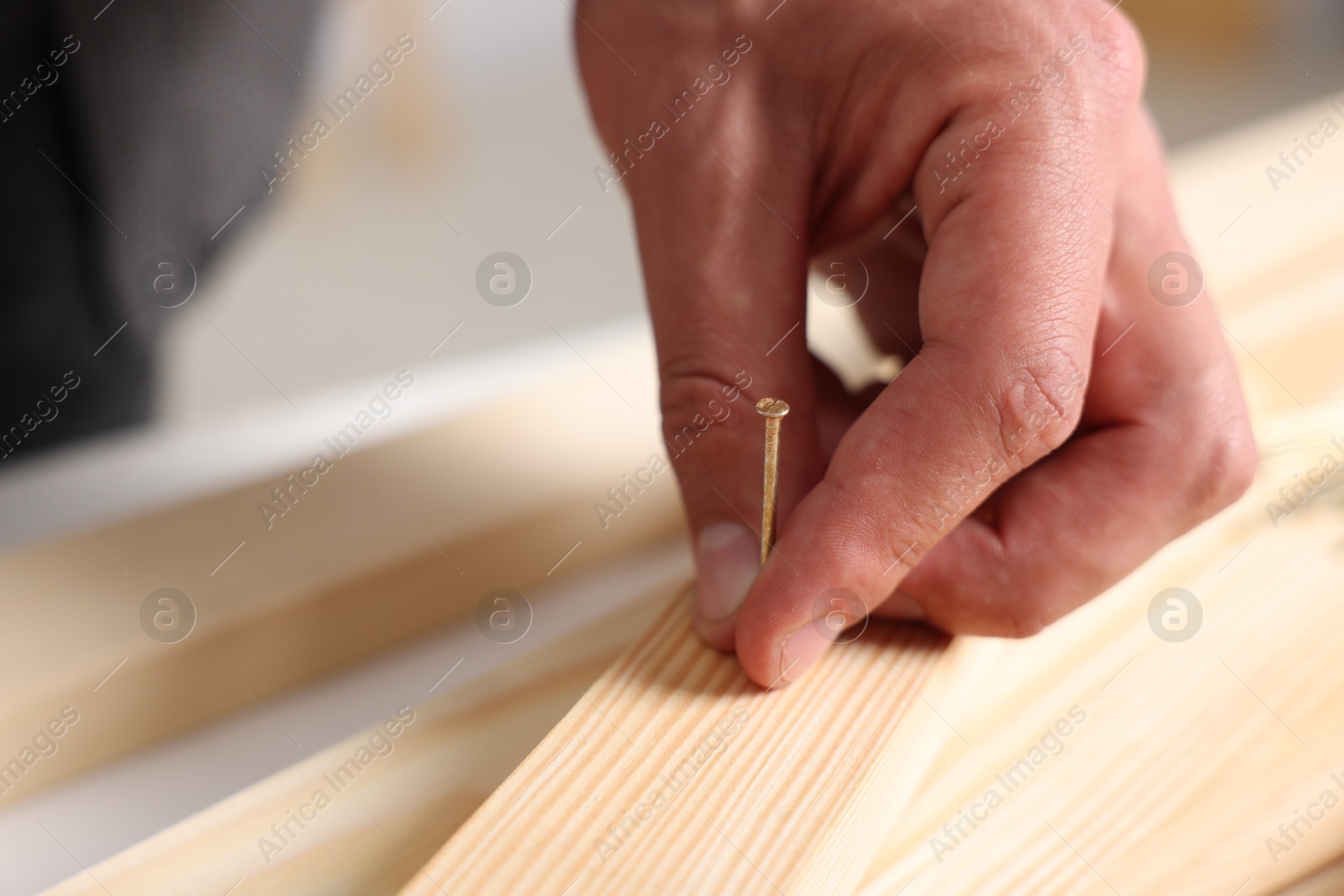 Man with metal nail and wooden planks at table indoors, closeup. Space for text Photo of Man with metal nail and wooden planks at table indoors, closeup. Space for text