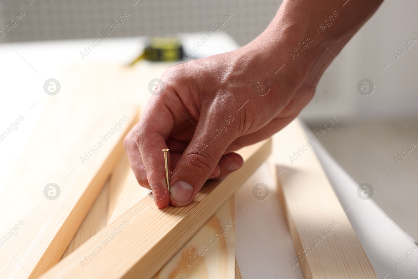 Man with metal nail and wooden planks at table indoors, closeup Photo of Man with metal nail and wooden planks at table indoors, closeup
