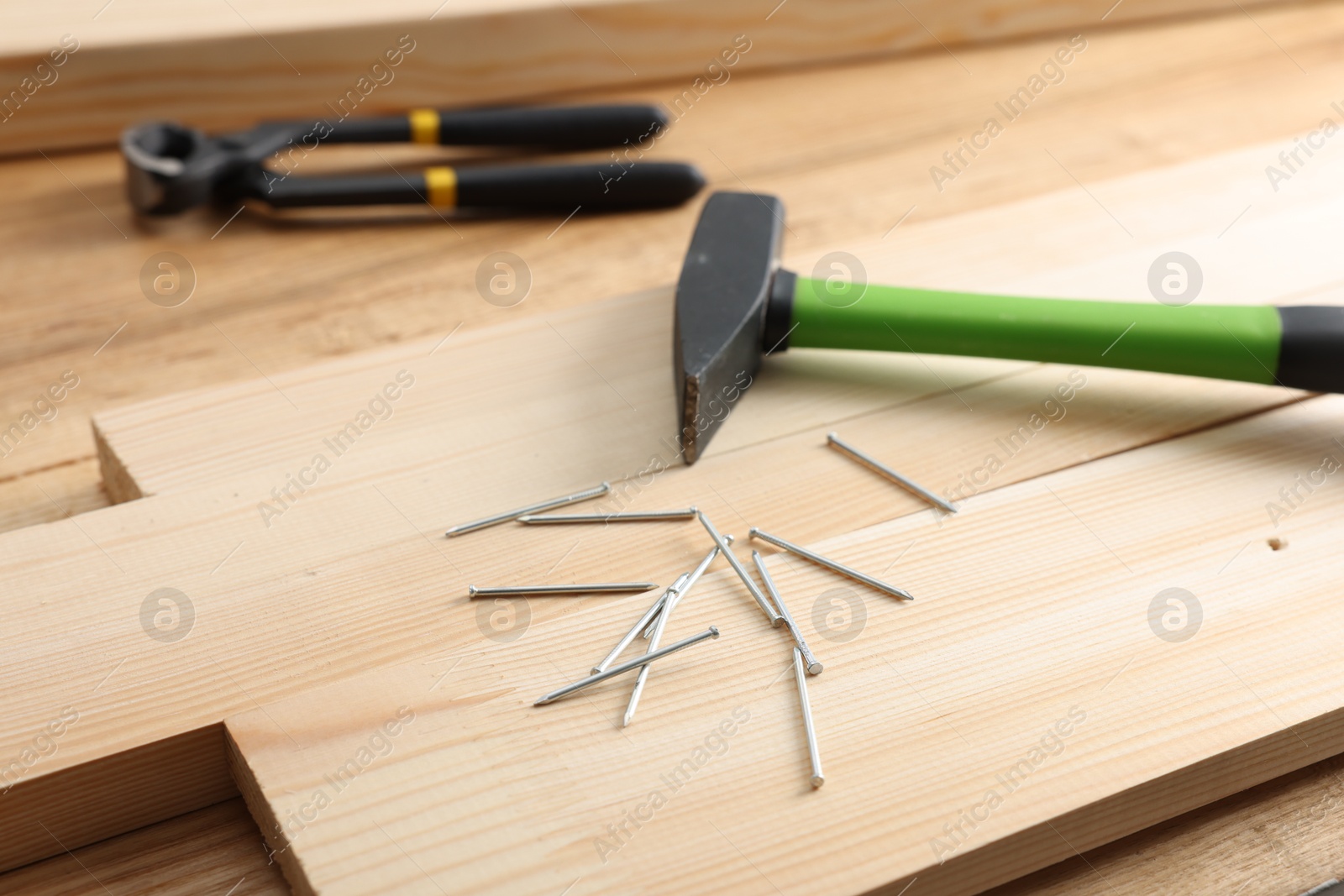 Metal nails, hammer, planks and pincers on wooden table, closeup Photo of Metal nails, hammer, planks and pincers on wooden table, closeup