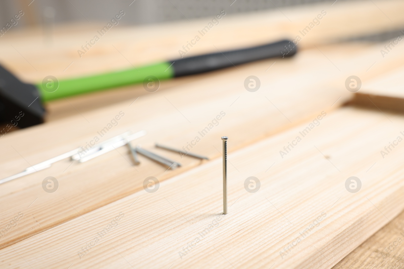 Metal nails, wooden planks and hammer on table, closeup Photo of Metal nails, wooden planks and hammer on table, closeup