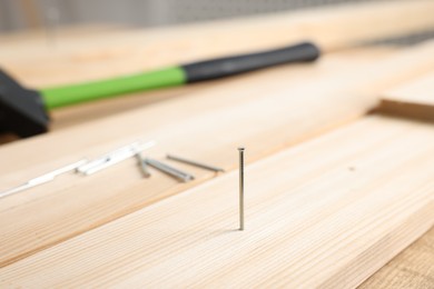 Photo of Metal nails, wooden planks and hammer on table, closeup