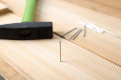 Photo of Metal nails, wooden planks and hammer on table, closeup